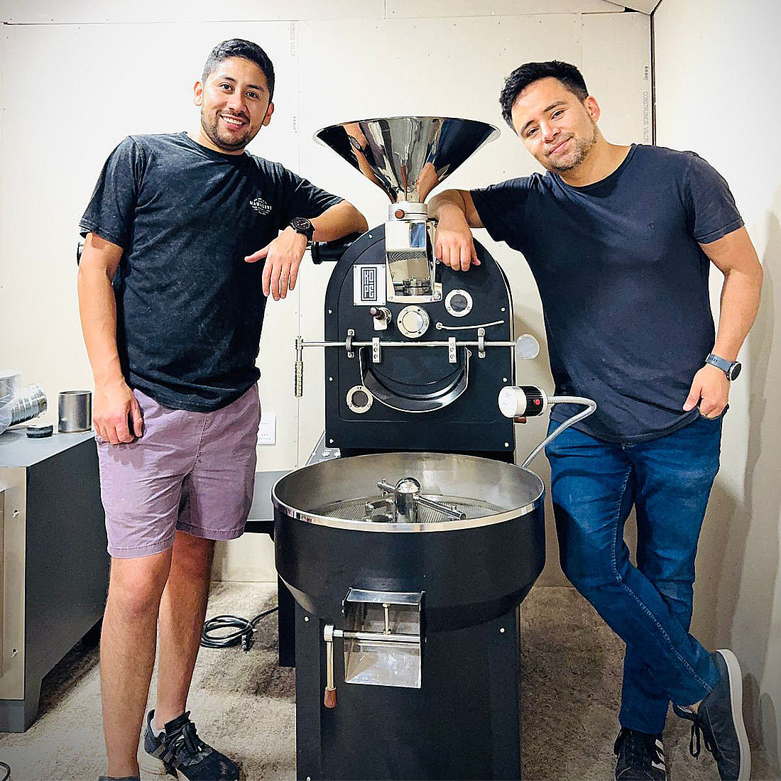 Two customers standing beside their coffee roasting machine